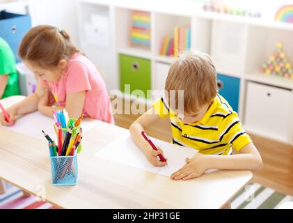Schoolkids in aula seduti ai tavoli e scrivere una lezione. Concetto di studio e apprendimento a scuola e asilo. Foto Stock