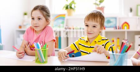 Schoolkids in aula seduti ai tavoli e ascoltando una lezione con interesse. Concetto di studio e apprendimento a scuola e asilo Foto Stock