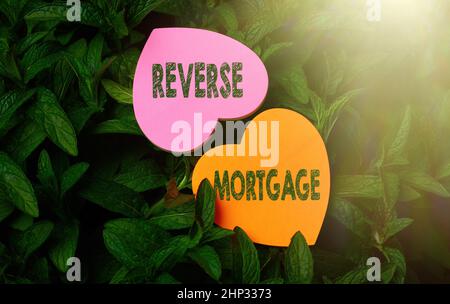 Testo che mostra ispirazione ipoteca inversa, prestito panoramica aziendale per anziani di età superiore agli anni sessanta e più vecchi per essere restituito cuore forma carta sulla parte superiore di Foto Stock