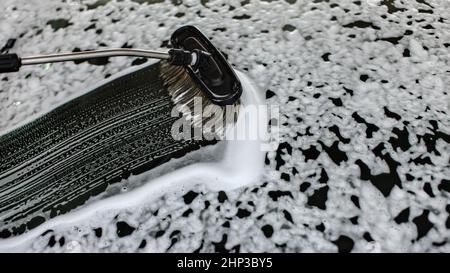 Pennello lasciando tratti nel sapone e schiuma sul vetro anteriore del vetro auto lavata al self service autolavaggi. Foto Stock