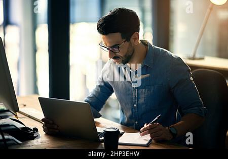 A questo tasso, inferno essere dipendente del mese. Scatto di un giovane uomo d'affari che usa un computer portatile durante una notte tarda al lavoro. Foto Stock