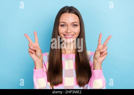 Foto di positivo bella felice carina donna mostrare due v-segno posa indossare abiti casual isolato blu sfondo colore Foto Stock