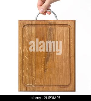 le mani femminili tengono il tagliere di legno rettangolare marrone vuoto su sfondo bianco Foto Stock