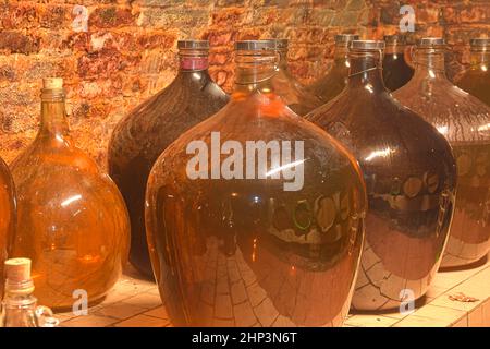 Demijohns vintage in una cantina tradizionale. Bottiglie di vino demijohn. Foto Stock