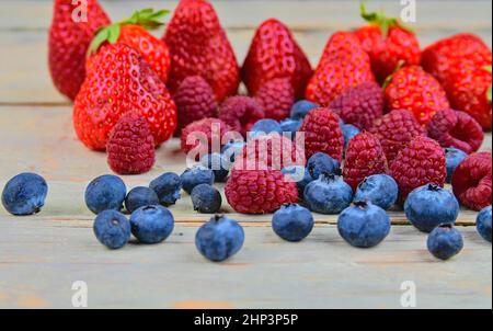 Frutta mista sana e ingredienti con fragola, lampone, mirtillo. Bacche su sfondo rustico bianco in legno. Primo piano. Immagine macro. Foto Stock