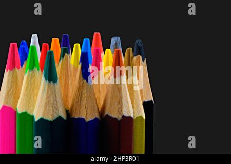 Close up di un assortimento di matite colorate suggerimenti su sfondo nero. Sfondo di matite colorate. Idea creativa e concetto. Disegno e pittura Foto Stock