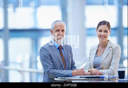 Vecchio talento, nuovo talento. Ritratto di un uomo d'affari maturo in piedi con una collega femminile più giovane. Foto Stock