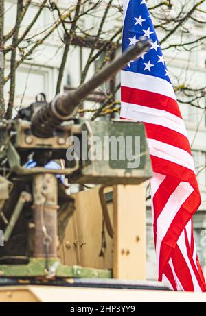 Mitragliatrice montata su un carro armato o un veicolo militare degli Stati Uniti d'America o dell'esercito degli Stati Uniti d'America, con la bandiera americana in esonero sullo sfondo, verticale Foto Stock