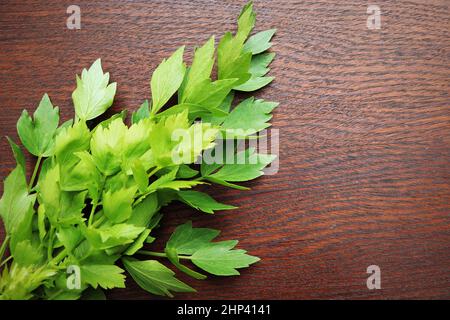 Foglie verdi fresche di lovage o di Levisticum officinale su tavola di legno . Foto Stock