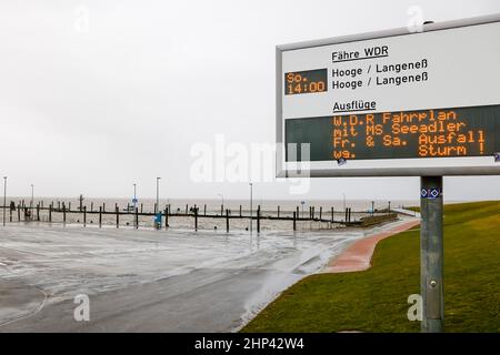 18 febbraio 2022, Schleswig-Holstein, Schlüttsiel: Dopo la pesante tempesta 'Ylenia' e prima del nuovo uragano 'Zeynep', i cambiamenti di orario sono esposti su un cartello informativo presso il terminal dei traghetti di Schlüttsiel. Foto: Frank Molter/dpa Foto Stock