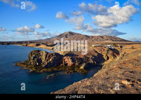 Costa de Papagayo a Lanzarote, Spagna, con i due bar e la catena montuosa Los Ajaches sullo sfondo. Una serata di sole con alcune nuvole in un b Foto Stock