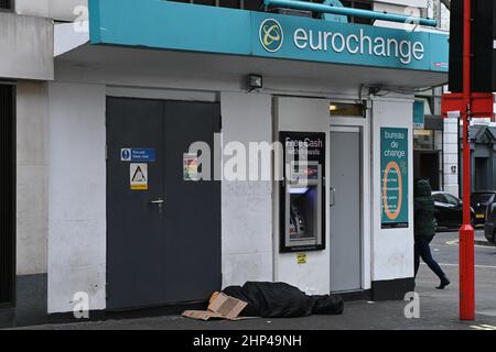 Londra, Regno Unito. 18th Feb 2022. London Weather, UK, 18 febbraio 2022. Una persona senza tetto dorme di fronte alla cash machine Euroschange in Leicester Square. Credit: Picture Capital/Alamy Live News Foto Stock