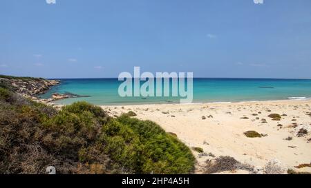 Vuoto bellissima e incontaminata spiaggia di sabbia fine con nessun popolo, vista dalla cima della collina di azzurro mare calmo. Karpass (Karpaz) regione, la parte settentrionale di Cipro. Foto Stock