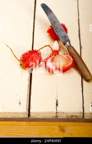 Tropicali freschi frutti di rambutan su tavola in legno rustico Foto Stock