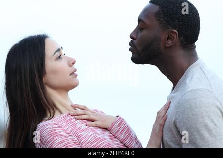 Ritratto di profilo di una donna che rifiuta un bacio da un uomo con pelle nera Foto Stock