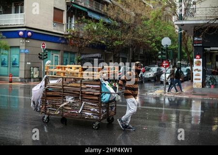 Un giovane che spinge un carrello con un carico di materiale riciclabile ad Atene in Grecia. Foto Stock