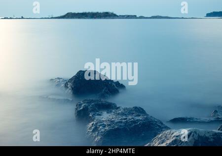 Le rocce che emergono dal mare sono illuminate dal sole al tramonto. Foto Stock