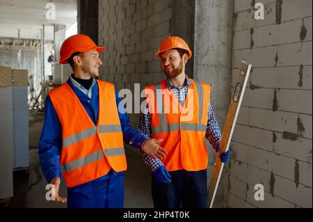 Due costruttori in uniforme camminare e parlare. Casa appartamento zona residenziale cantiere Foto Stock