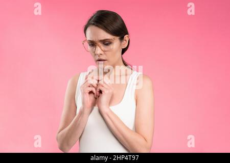 Soffrendo di mal di testa o emicrania giovane donna in manica rosa t-shirt che tiene la testa con gli occhi chiusi isolato su sfondo rosa. Donna dipendente stressata in abito a strisce. Con spazio di copia. Foto Stock