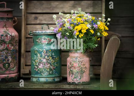 Vecchie caraffe di latte su una panca da giardino Foto Stock