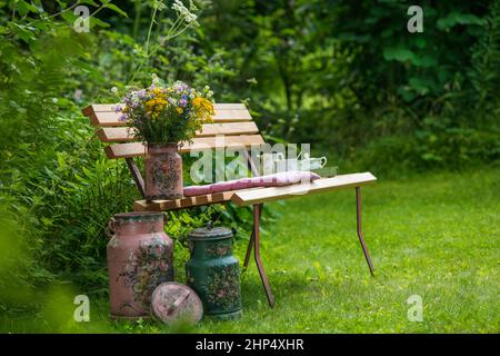 Vecchie caraffe di latte su una panca da giardino Foto Stock