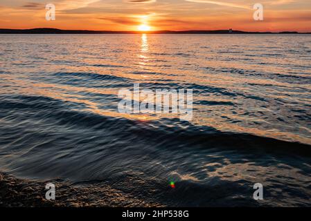 I raggi del sole si riflettono nell'acqua al tramonto Foto Stock