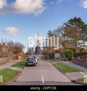 Un mulino a vento funzionante di 18th secolo situato in una strada residenziale. Una strada conduce al mulino e le case sono su entrambi i lati. Un cielo blu con la nuvola sopra. Foto Stock