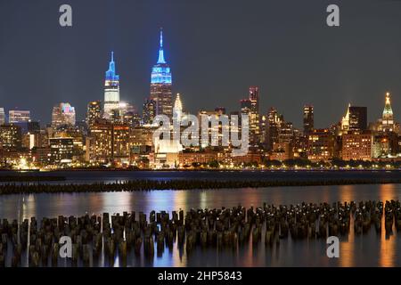 I grattacieli storici di New York illuminati di notte dall'altra parte del fiume Hudson. Paesaggio urbano di West Village e Midtown Manhattan Foto Stock