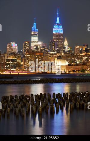 I grattacieli storici di New York illuminati di notte dall'altra parte del fiume Hudson. Paesaggio urbano di West Village e Midtown Manhattan Foto Stock