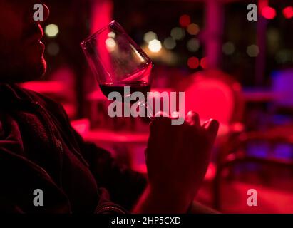 L'uomo beve vino rosso in un club Foto Stock