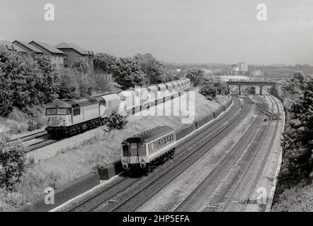 Una locomotiva diesel classe 56 numero 56056 scende Acton Bank con le tramogge di pietra ARC vuote, mentre la DMU classe 121 auto bolla numero L128 è passato sotto un servizio di rete sud-est. 10th giugno 1991. Foto Stock