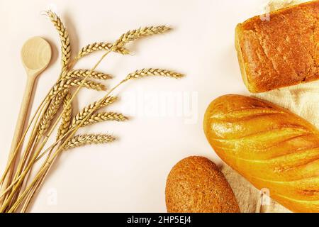 Orecchie di grano maturo e tre diversi pani di pane Foto Stock