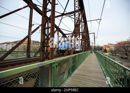 Locomotiva di classe 162 delle Ferrovie ceche di Ceske Drahy che attraversano il fiume Moldava, con passerella pedonale in legno oltre ai binari, Praga, repubblica Ceca Foto Stock