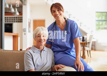 Fornire grande cura ai suoi pazienti. Scatto ritagliato di un'infermiera seduta accanto al paziente anziano. Foto Stock