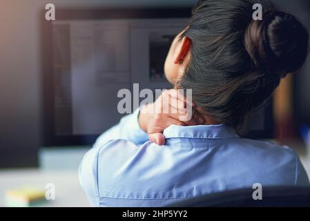 Sentire lo sforzo. Colpo di retroripiano di una donna d'affari che soffre di dolore al collo in ufficio. Foto Stock