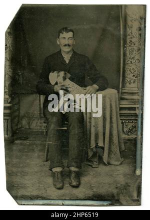 Antica fotografia di tintype circa 1860, un uomo con un piccolo cane in grembo. Località sconosciuta, Stati Uniti. FONTE: TINTYPE ORIGINALE Foto Stock
