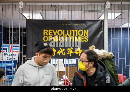 Toronto, Canada. 18th Feb 2022. Gli uomini che indossano maschere sono visti parlare di fronte a una bandiera 'Rivoluzione dei nostri tempi' a Toronto.Toronto HK Club ospita una proiezione della 'Rivoluzione dei nostri tempi' un documentario controverso sulle 2019-2020 proteste di Hong Kong diretto da Kiwi Chow, a Toronto, Canada. Prima premiazione ad una sorpresa che mostra al Festival di Cannes, i biglietti sono stati venduti in proiezioni in tutto il Canada mentre sono stati vietati in Cina e Hong Kong. (Foto di Katherine Cheng/SOPA Images/Sipa USA) Credit: Sipa USA/Alamy Live News Foto Stock