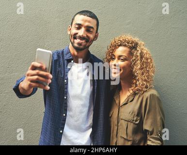 Catturare i momenti per guardarli in un secondo momento. Scatto di una giovane coppia che prende un selfie insieme fuori. Foto Stock