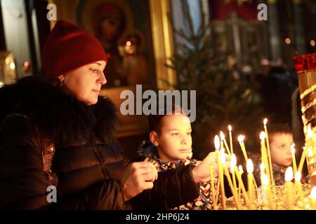 Ritratto di madre e figli con candele nella chiesa ortodossa russa Foto Stock
