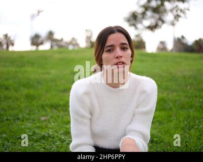 Una giovane donna nel parco che guarda la telecamera che riceve cattive notizie Foto Stock