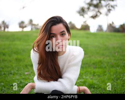 Una giovane donna arrabbiata nel parco che guarda seriamente la telecamera Foto Stock