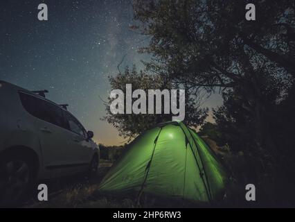 Campeggio con auto e tenda sotto il cielo stellato Foto Stock