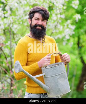 Lavoro di giardiniere. Agricoltore che lavora in giardino. L'uomo bearded con annaffiatura può prepararsi a piantare. Molla. Foto Stock