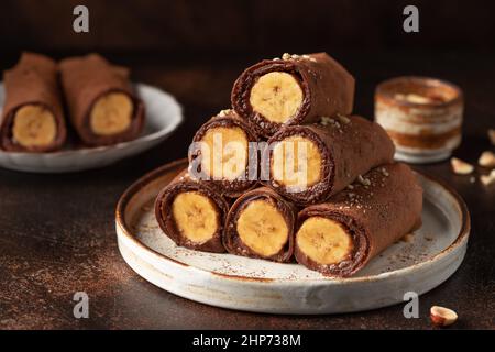 Crepes di cioccolato vegano arrotolato con ripieno di banana Foto Stock