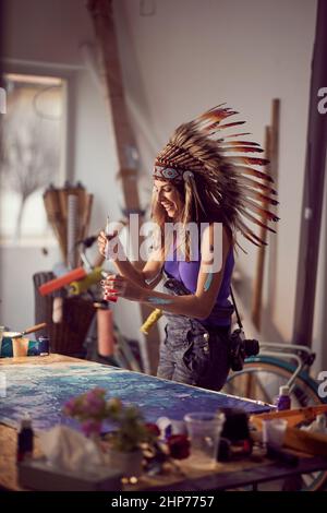 Una giovane artista femminile con un cofano da guerra in un'atmosfera piacevole nello studio sta avendo un buon tempo mentre lavora al suo nuovo dipinto. Arte, pittura, Foto Stock