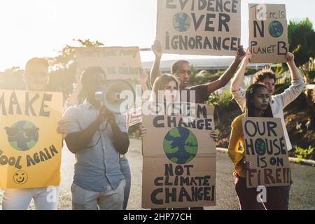 Gruppo di attivisti che protestano per il cambiamento climatico - persone multirazziali che combattono su strada tenendo striscioni su disastri ambientali Foto Stock