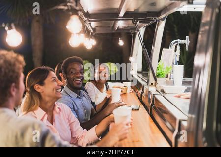 Felice gente multirazziale che compra pasto dalla cucina del camion del cibo - commercio moderno e concetto di take away Foto Stock