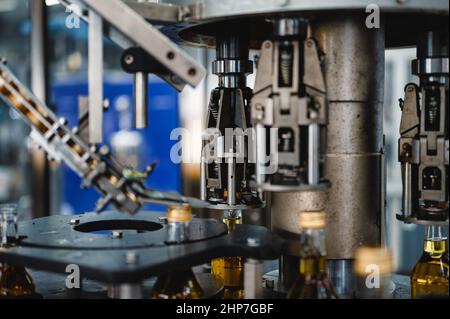 L'apparecchiatura automatica mette i tappi sulle bottiglie di bevande alcoliche Foto Stock