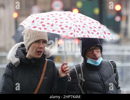 I membri del pubblico rinforzano il vento e il tempo umido nel centro di Westminster a Londra, seguendo Storm Eunice. Data immagine: Venerdì 18 febbraio 2022. Foto Stock