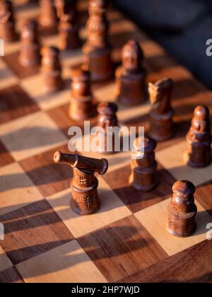 Scacchiera in legno con pezzi di legno alla luce del sole. Fuoco selettivo su Black Rook Foto Stock